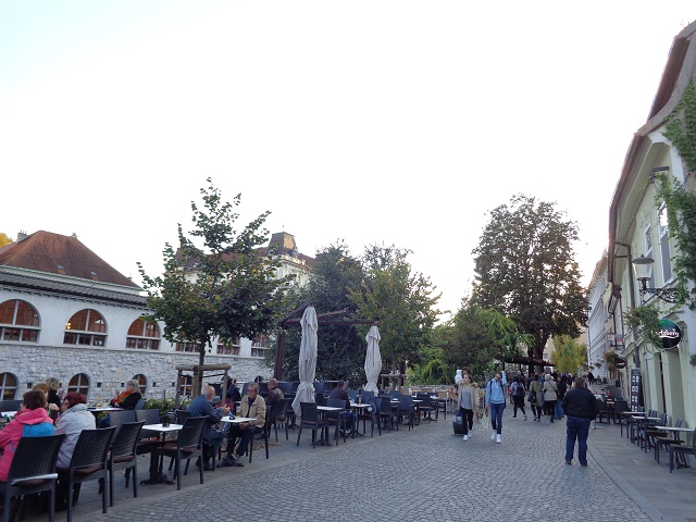 On the riverbank of Ljubljana, people out and about to enjoy the mild Autumn evening in an outdoor restaurant. The atmosphere and lively and energetic!
